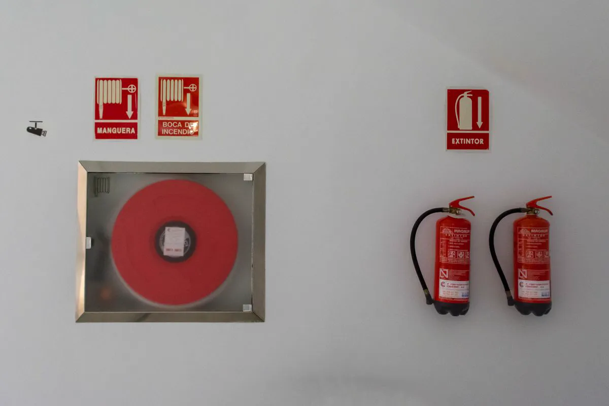 Abrigo de mangotinho com carretel e extintores portáteis instalados em parede com sinalização de equipamento de combate a incêndio
