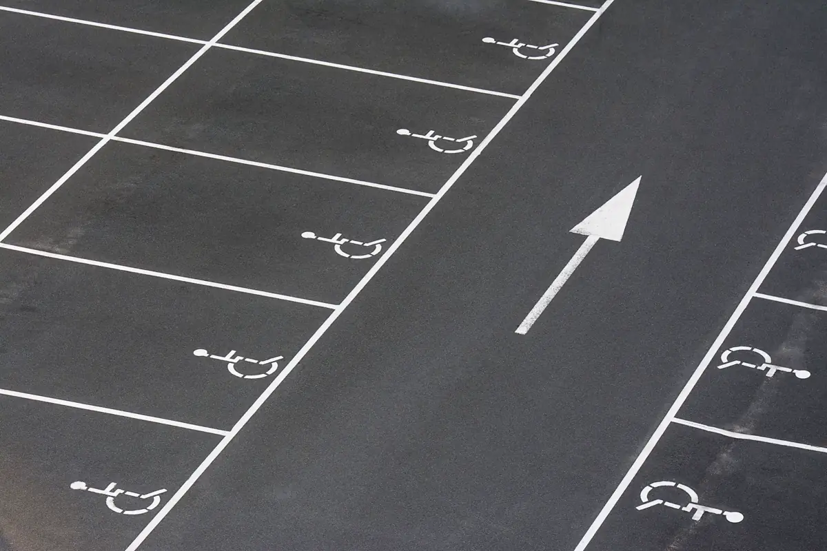 Estacionamento com sequência de vagas demarcadas com o símbolo de acesso e seta de circulação