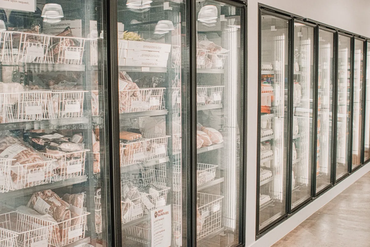 Expositores refrigerados com portas de vidro e produtos congelados organizados em prateleiras
