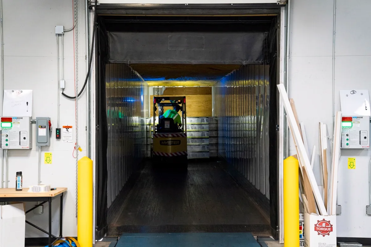 Empilhadeira movimentando carga paletizada em doca de armazém refrigerado
