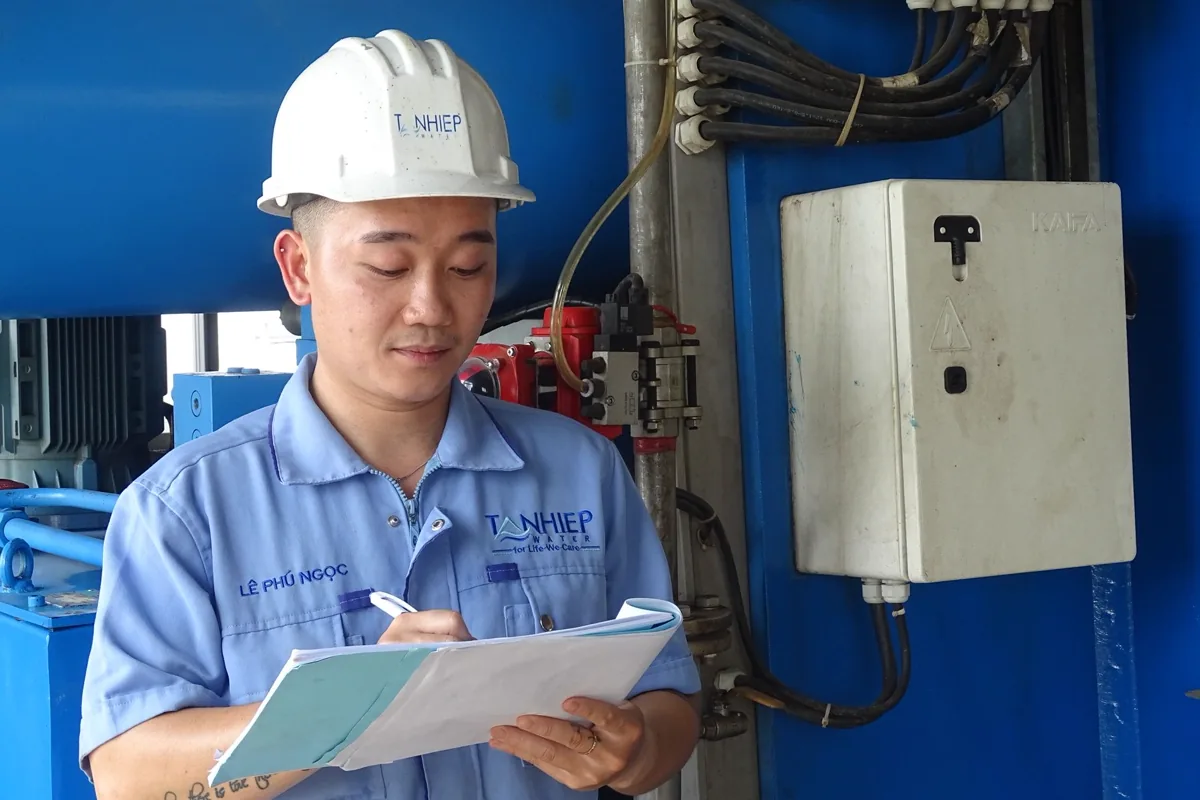 Engenheiro de EPI anotando observações durante inspeção de equipamento industrial