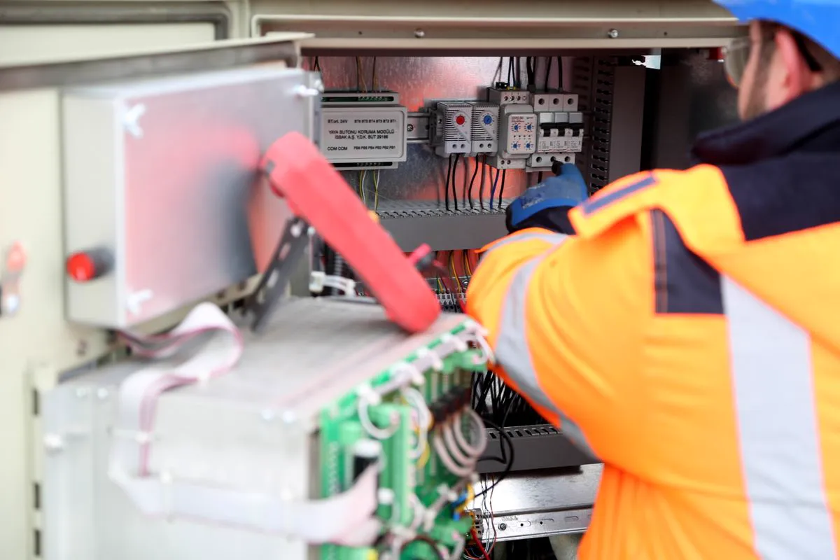 Engenheiro inspecionando painel elétrico industrial durante serviço de instalação e adequação de circuitos de segurança