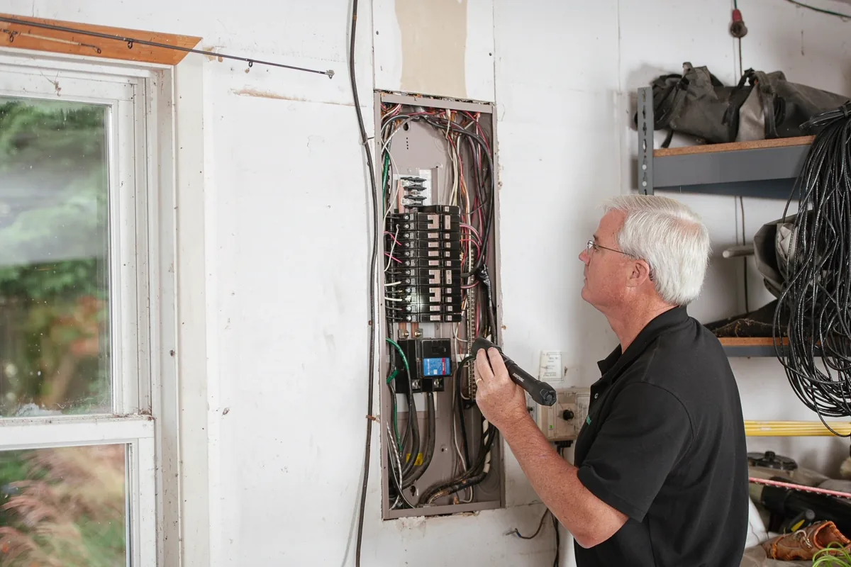 Eletricista verificando o quadro de distribuição e os disjuntores de uma edificação