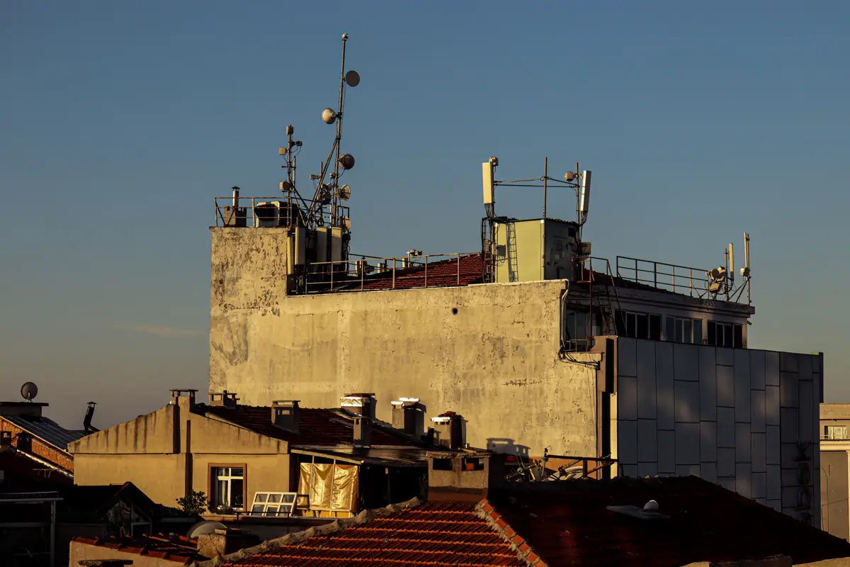 Cobertura de edifício com antenas e mastros iluminados pelo sol do fim de tarde
